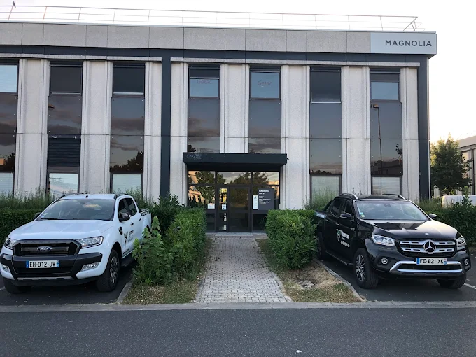 Façade et entrée du bâtiment Magnolia à Villebon-sur-Yvette abritant Vermeer France, avec véhicules de service stationnés.