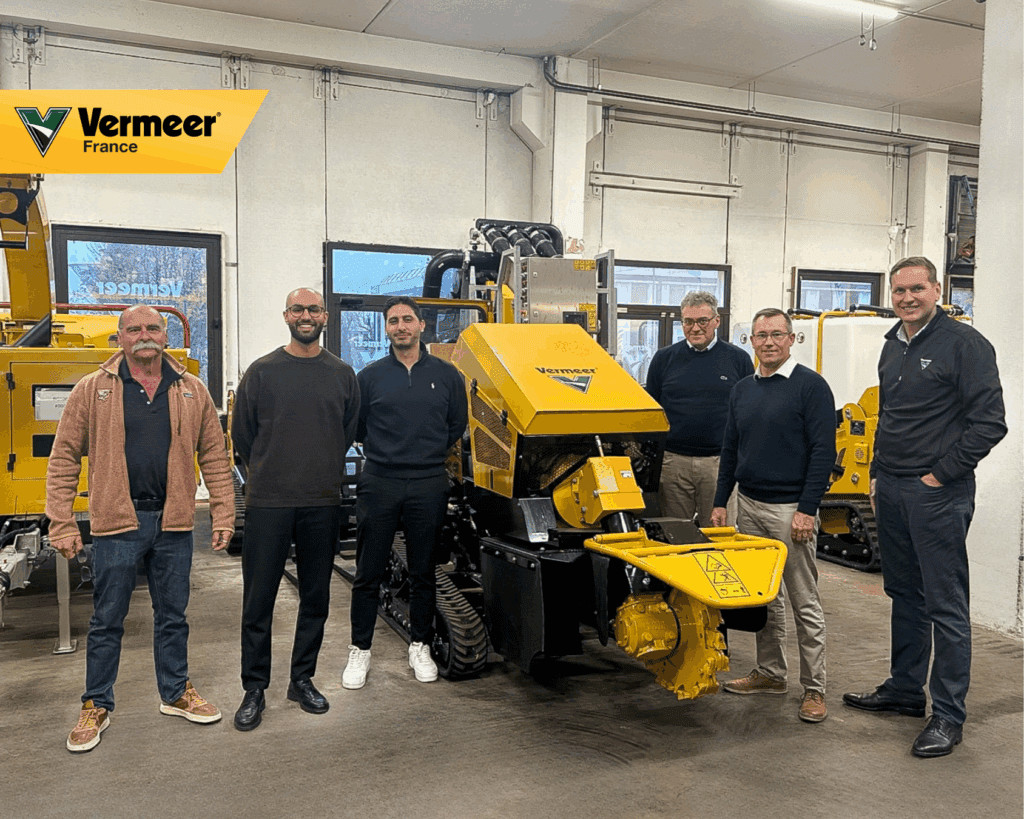 Six personnes posent dans l’atelier Vermeer France devant une machine jaune (équipement Vermeer) ; photo de groupe lors d’une réunion professionnelle avec Vermeer France, Vermeer Corporation et le partenaire financier DLL.